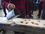 Le sucrier verse le sirop bouillant sur la neige, Fêtes des sucres, Saint-Aubert, 2016.